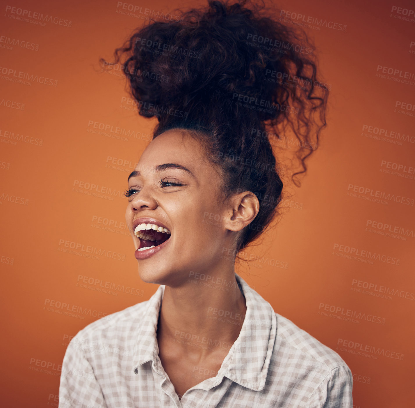 Buy stock photo Shot of a young woman wearing her hair in a bun against an orange background