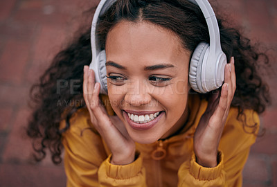 Buy stock photo Cropped shot of a beautiful young woman wearing headphones while standing outside