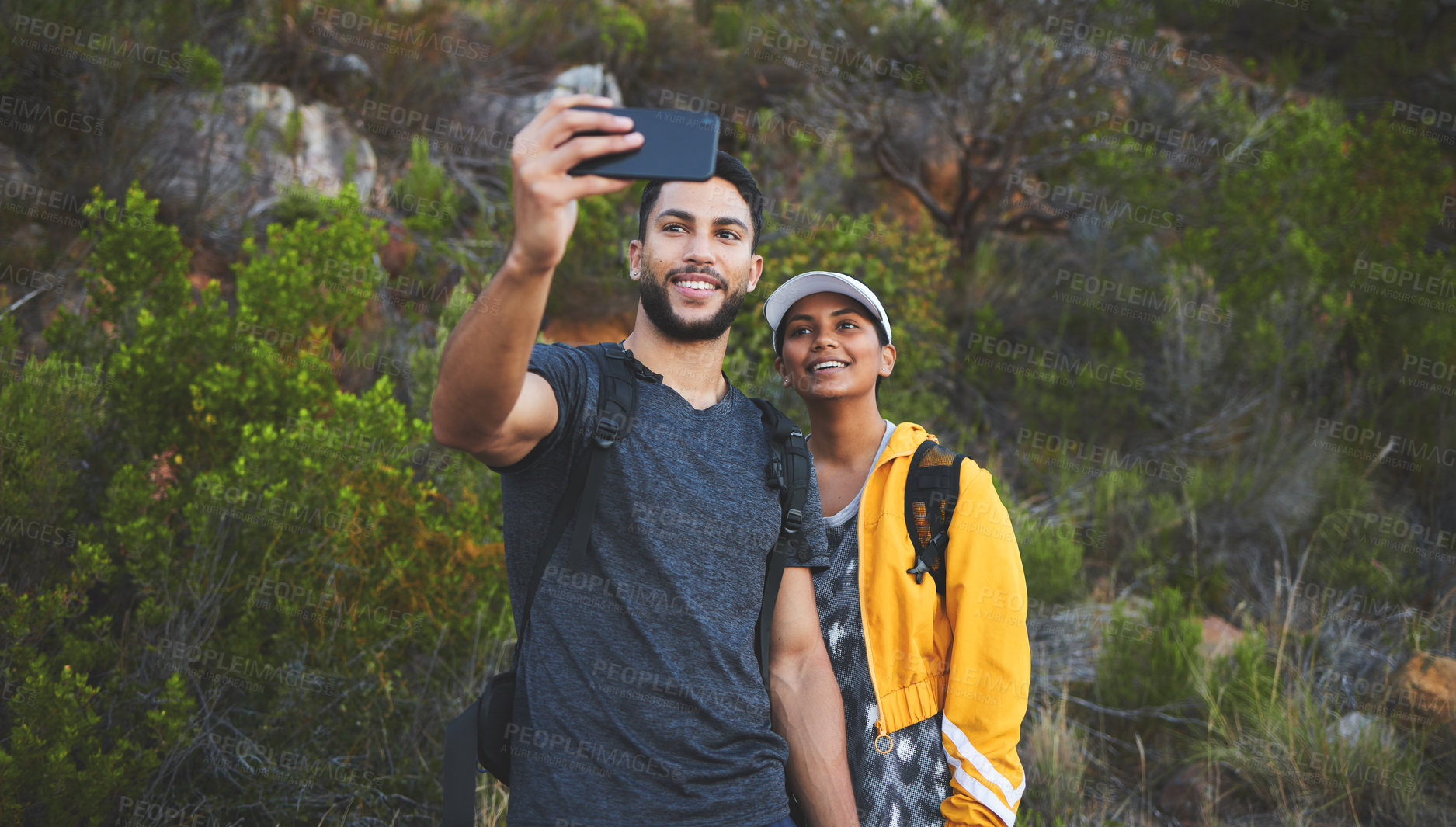 Buy stock photo Shot of a young couple taking photos while out on a hike in a mountain range outside