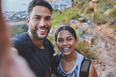 Buy stock photo Shot of a young couple taking photos while out on a hike in a mountain range outside