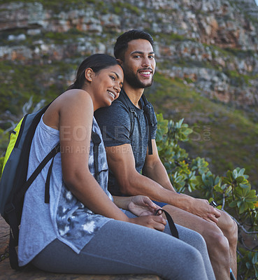 Buy stock photo Shot of a young couple enjoying the sunset view while out on a hike on a mountain range