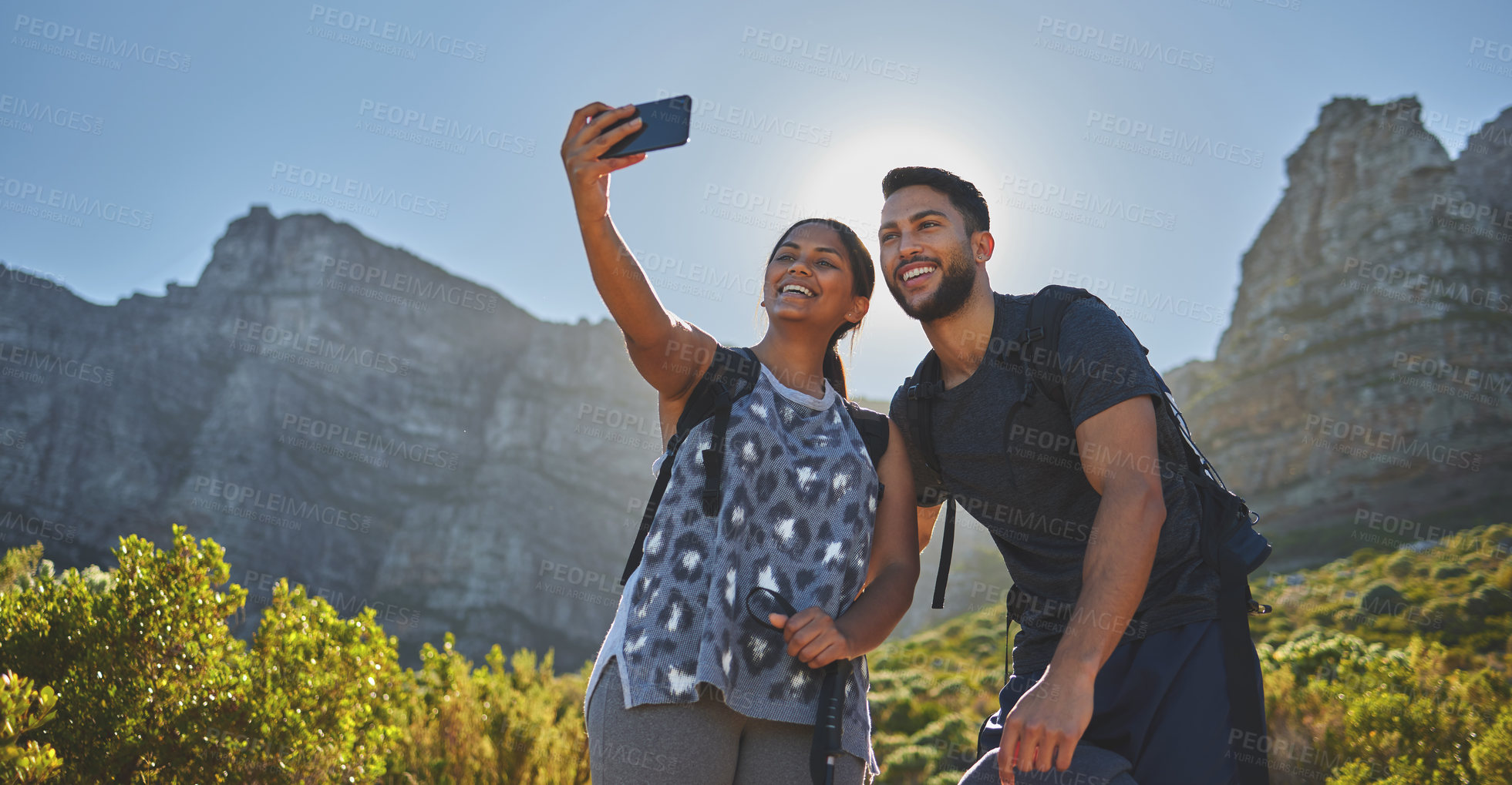 Buy stock photo Shot of a young couple taking photos while out on a hike in a mountain range outside