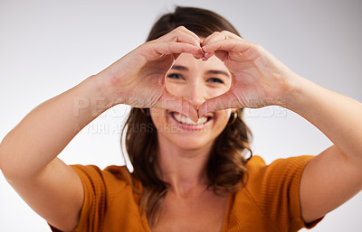 Buy stock photo Happy woman, portrait and heart hands with love for romance, care or kindness on a gray studio background. Young female person with smile for hearty shape, like emoji and romantic gesture or symbol