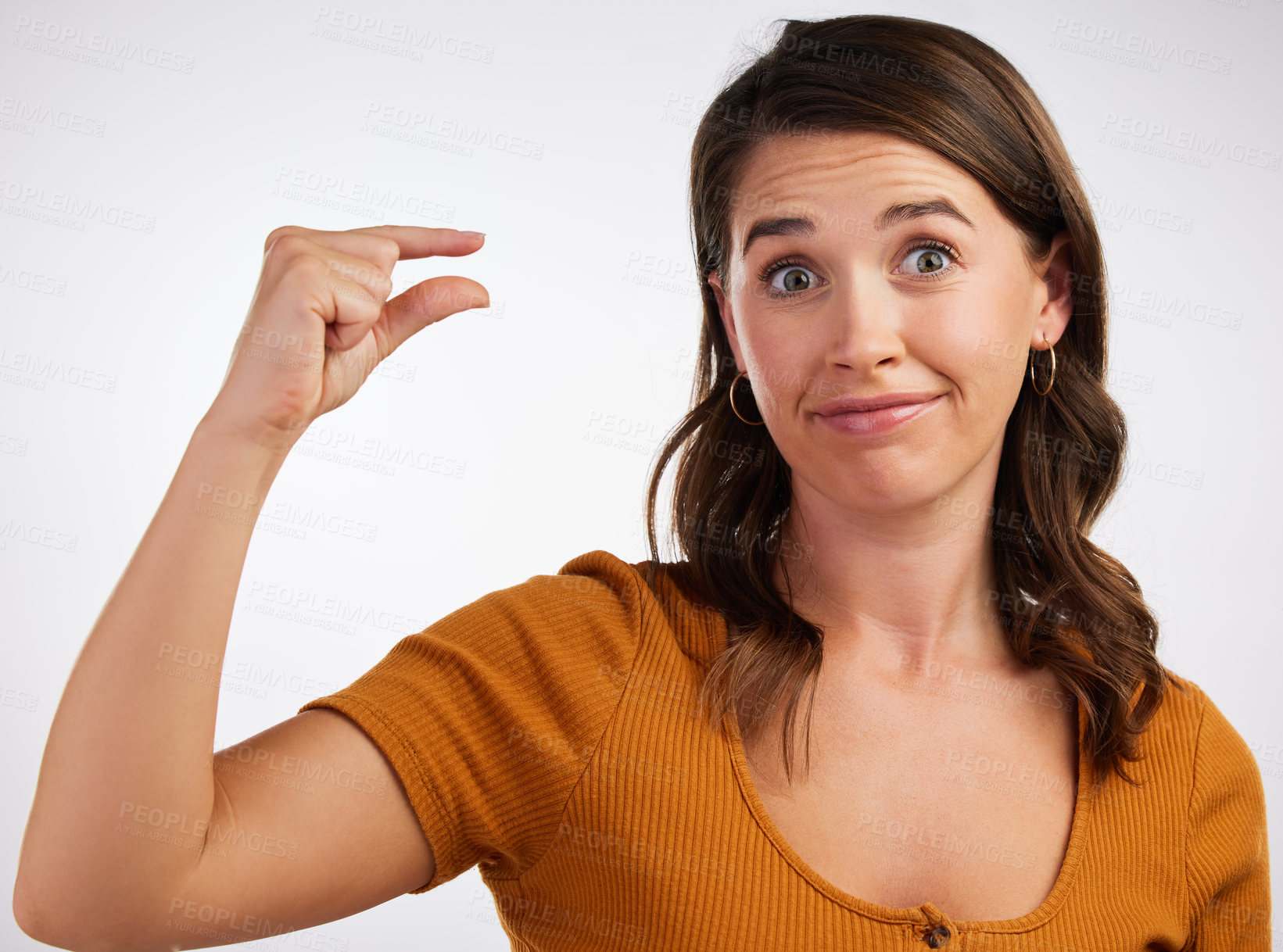 Buy stock photo Studio shot of a young woman gesturing a small size with her hand against a white background