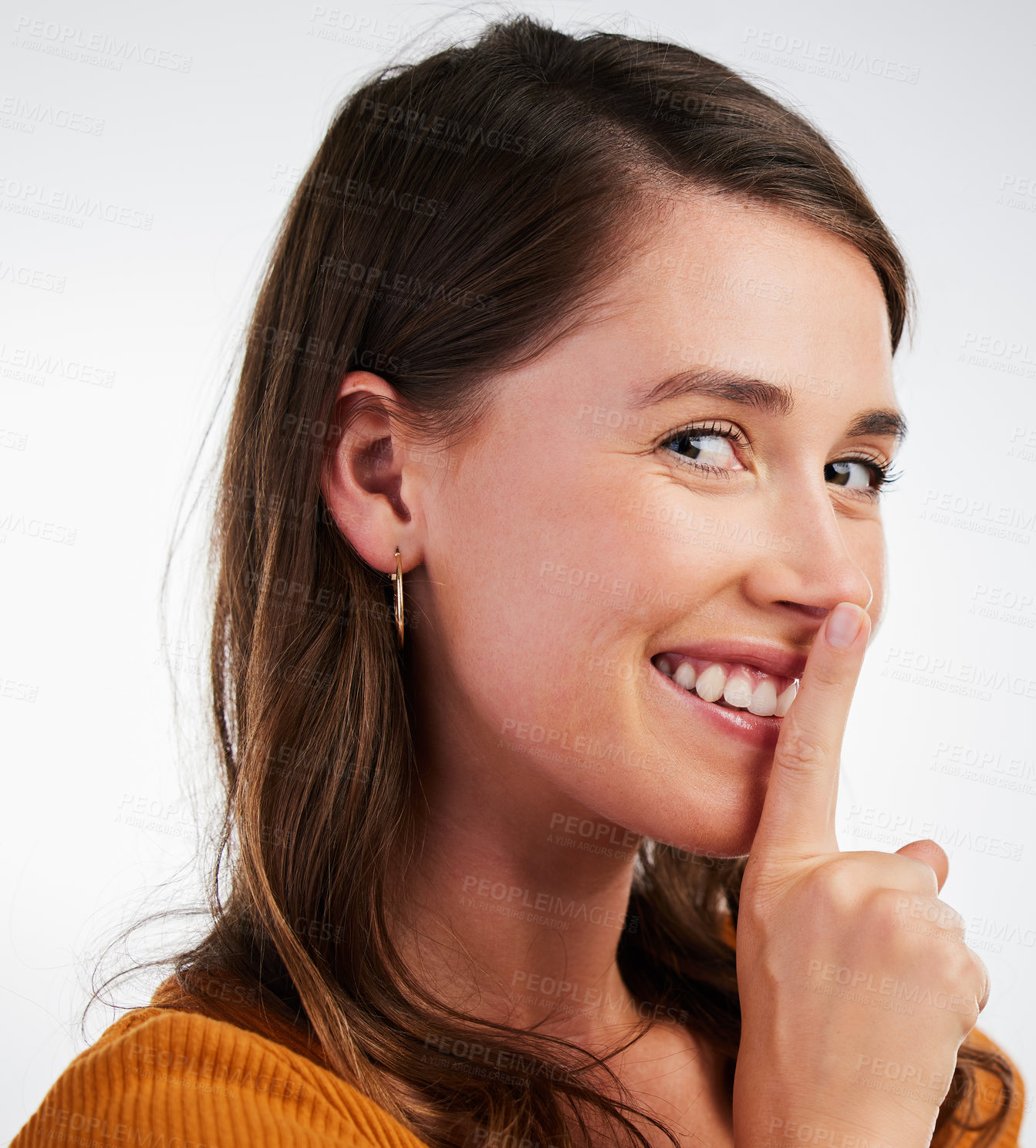 Buy stock photo Studio shot of a young woman smiling and signalling to be quiet against a background