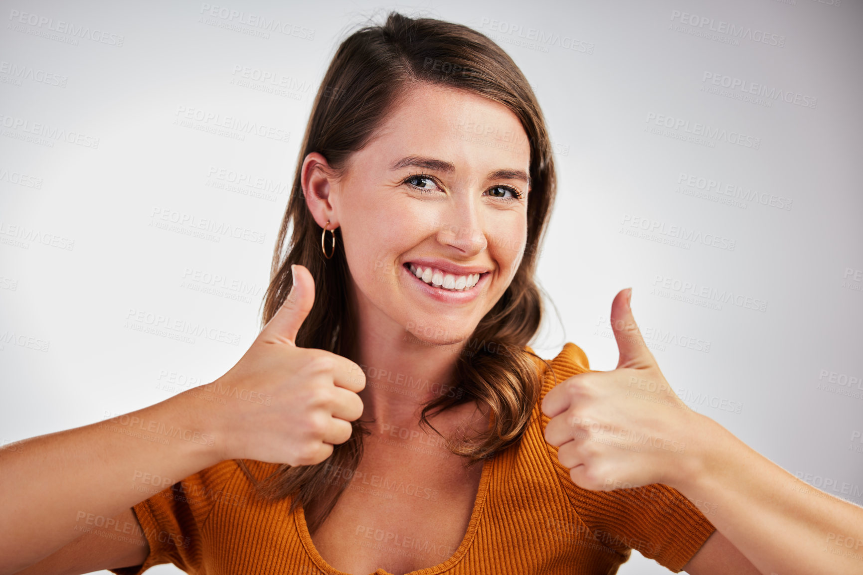 Buy stock photo Studio shot of a young woman showing thumbs up against a white background