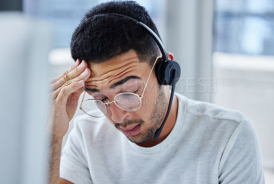Buy stock photo Shot of a young businessman suffering s headache at his desk in his office