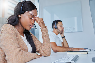 Buy stock photo Shot of male and female team members sitting at their desks in their call center office