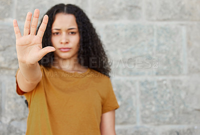 Buy stock photo Shot of a young woman showing the stop gesture while standing outside