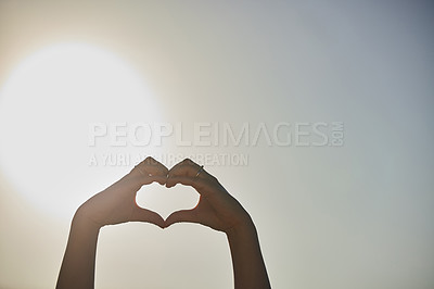 Buy stock photo Cropped shot of a woman forming a heart shape with her hands against a blue sky