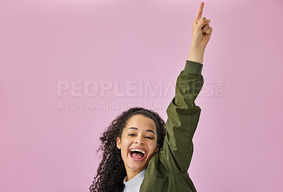 Buy stock photo Shot of an attractive young woman standing alone against a pink background in the studio and pointing upwards