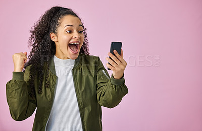 Buy stock photo Phone, space and winner with woman on pink background in studio for celebration of bonus. Emoji, fist and mockup with happy person cheering for good news or success on mobile app and social media