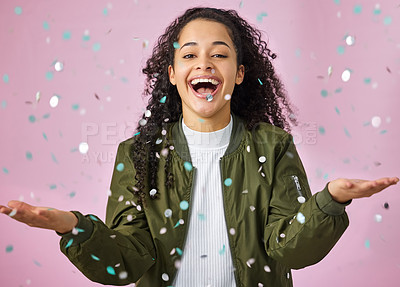 Buy stock photo Shot of an attractive young woman standing alone against a pink background in the studio while confetti falls around her
