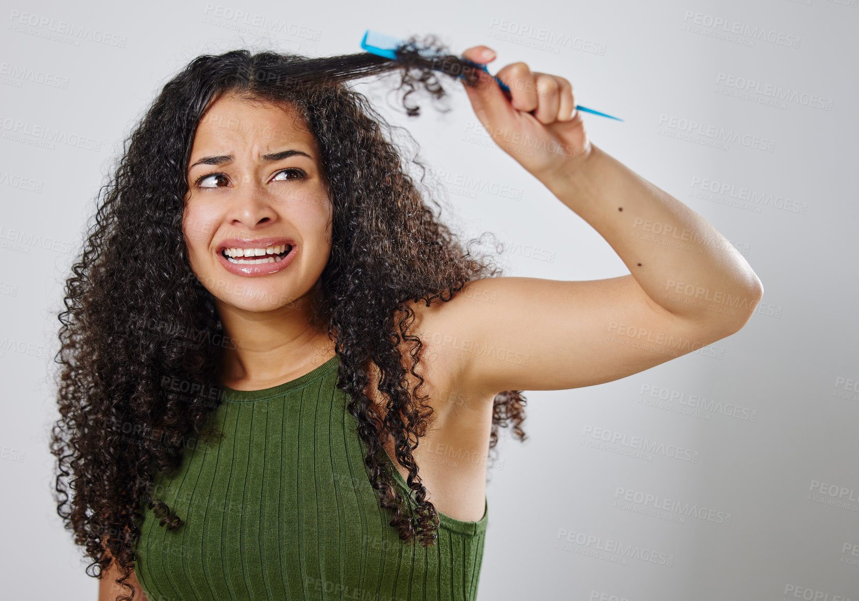 Buy stock photo Shot of a woman frowning while combing her hair against a grey background