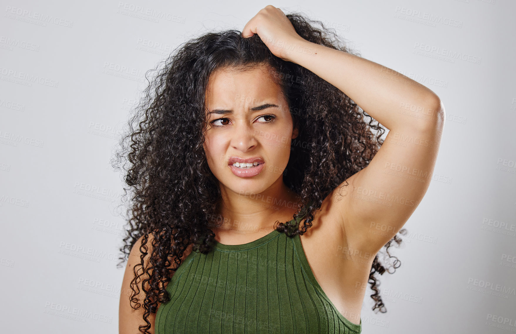 Buy stock photo Shot of a woman with curly hair frowning against a grey background