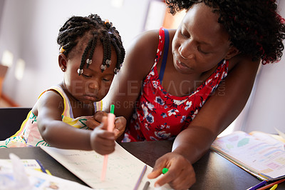 Buy stock photo Shot of a mother spending time with her daughter while colours in a book
