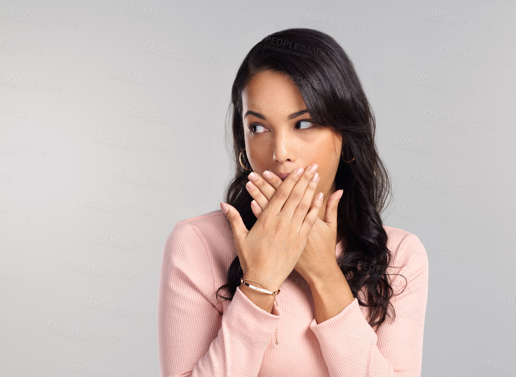 Buy stock photo Shot of a beautiful young woman looking surprised while standing against a grey background