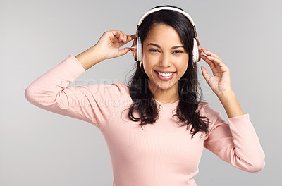 Buy stock photo Shot of a beautiful young woman wearing headphones while standing against a grey background