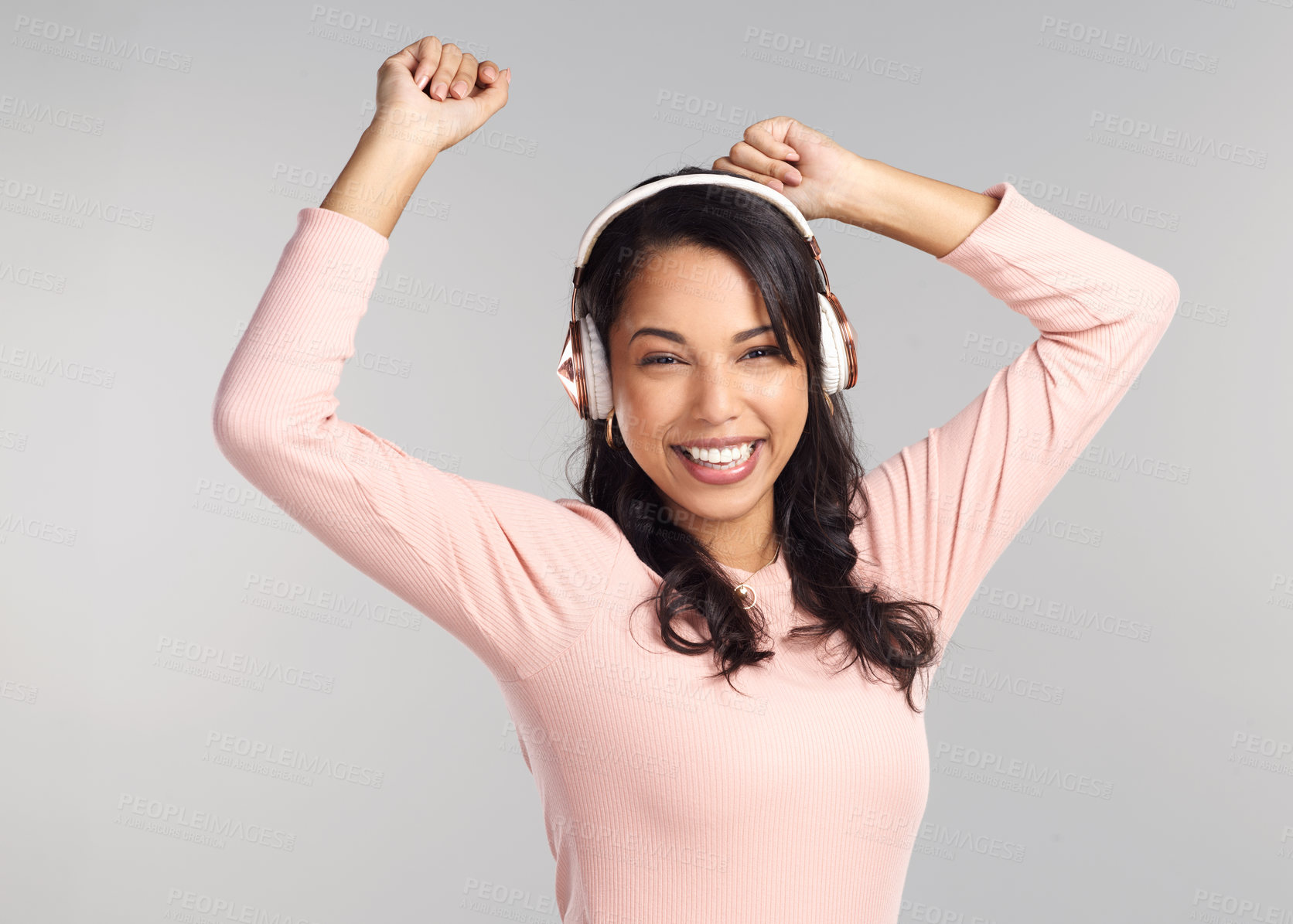 Buy stock photo Shot of a beautiful young woman wearing headphones while standing against a grey background