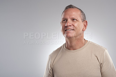 Buy stock photo Shot of a handsome mature man standing alone against a grey background in the studio and looking contemplative