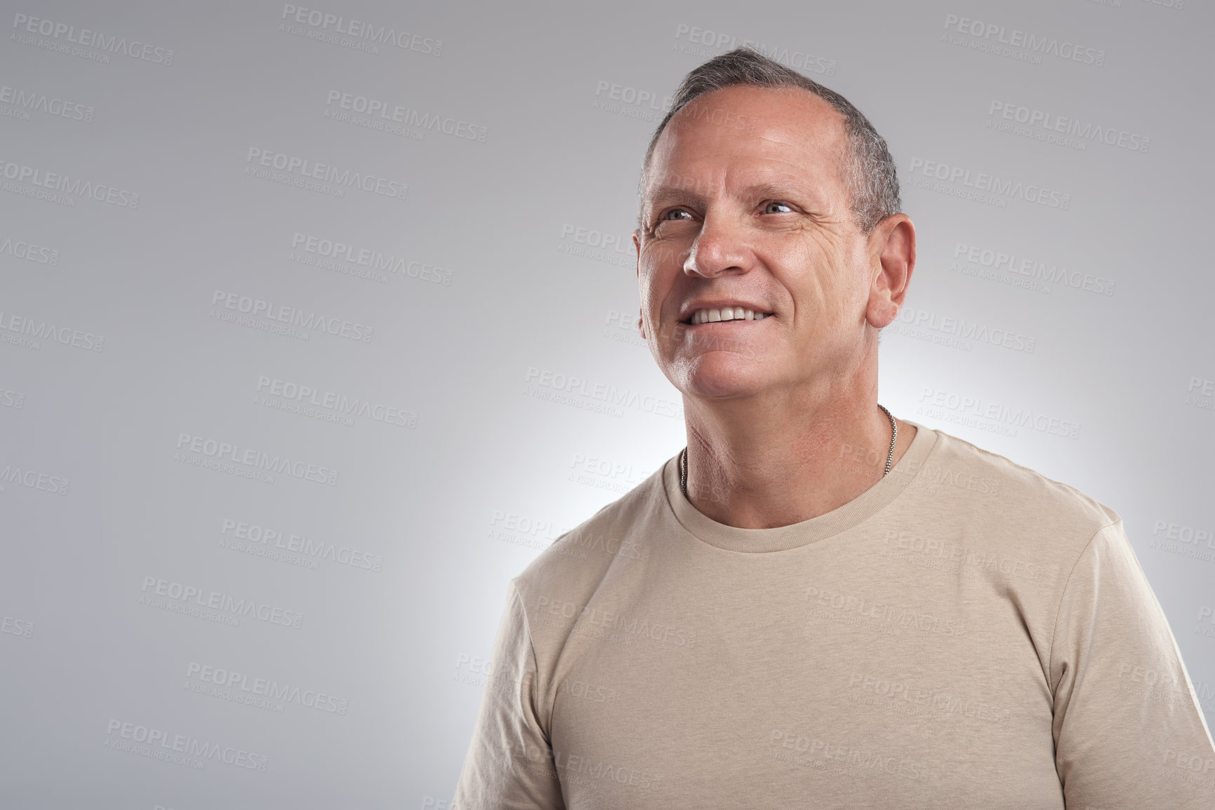 Buy stock photo Shot of a handsome mature man standing alone against a grey background in the studio and looking contemplative