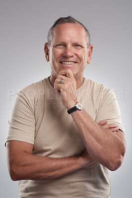 Buy stock photo Shot of a handsome mature man standing alone against a grey background in the studio and looking contemplative