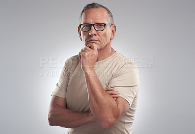 Buy stock photo Shot of a handsome mature man standing alone against a grey background in the studio and looking contemplative