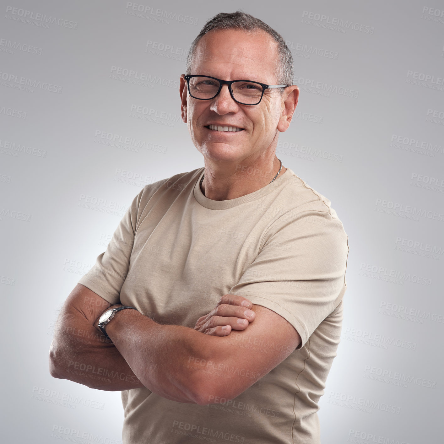 Buy stock photo Shot of a handsome mature man standing alone against a grey background in the studio with his arms folded