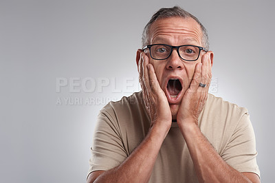 Buy stock photo Shot of a handsome mature man standing alone against a grey background in the studio and looking shocked