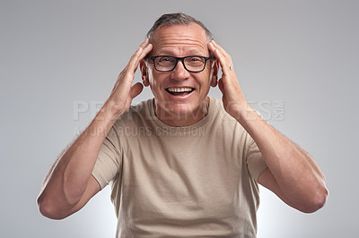 Buy stock photo Shot of a handsome mature man standing alone against a grey background in the studio and looking surprised