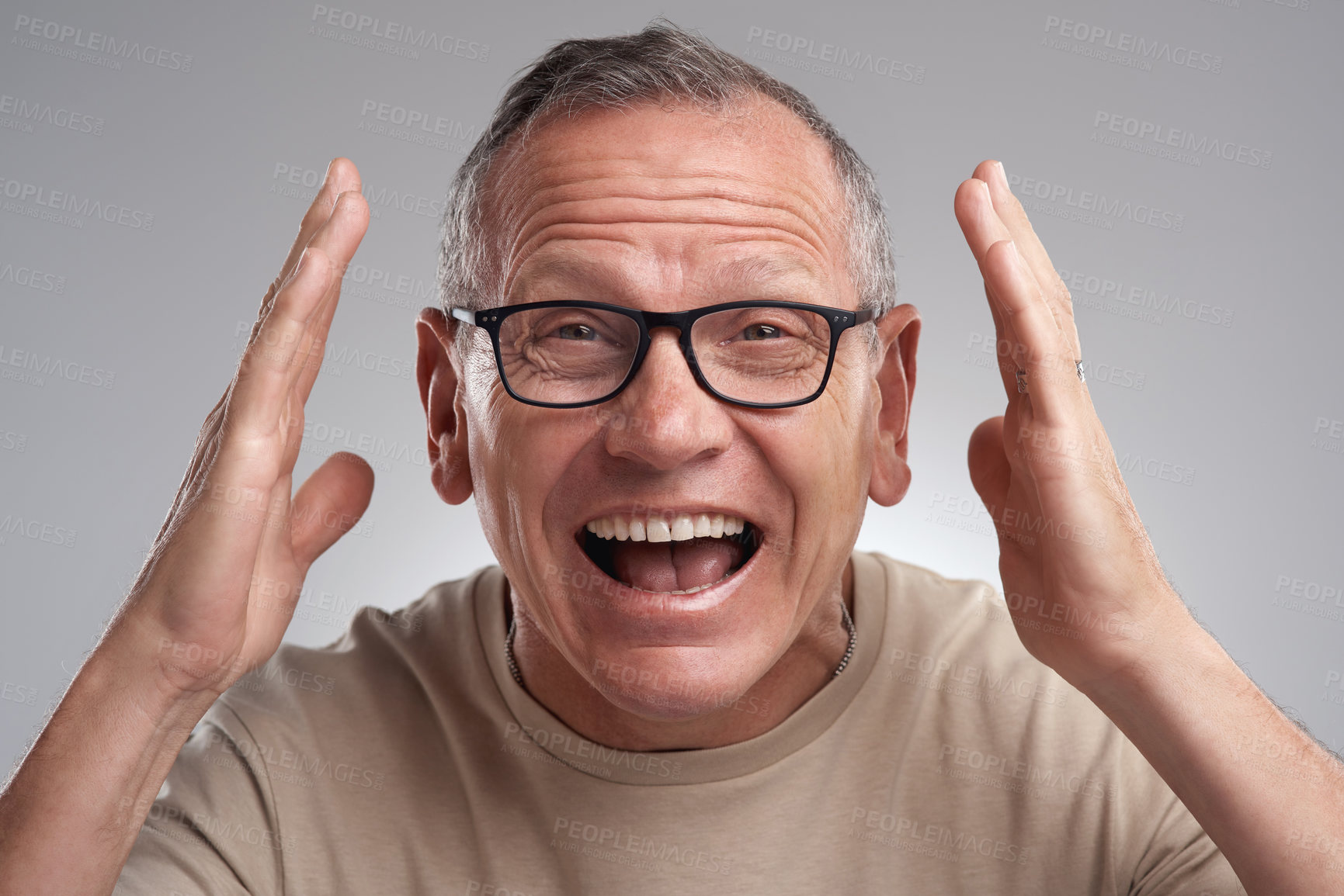 Buy stock photo Shot of a handsome mature man standing alone against a grey background in the studio and looking surprised