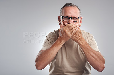 Buy stock photo Shot of a mature man standing against a grey background in the studio and covering his mouth with his hands