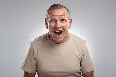 Buy stock photo Shot of a handsome mature man standing alone against a grey background in the studio and looking surprised