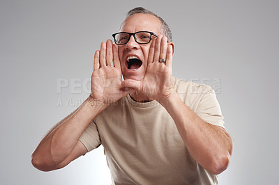 Buy stock photo Shot of a handsome mature man standing alone against a grey background in the studio and shouting