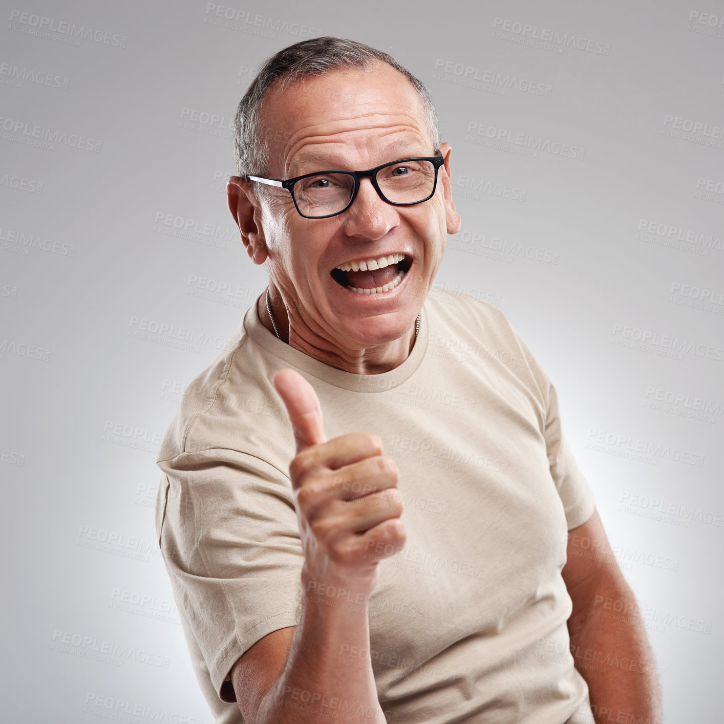 Buy stock photo Shot of a handsome mature man standing against a grey background in the studio and making a thumbs up gesture