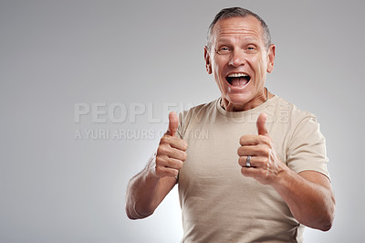 Buy stock photo Shot of a handsome mature man standing against a grey background in the studio and making a thumbs up gesture