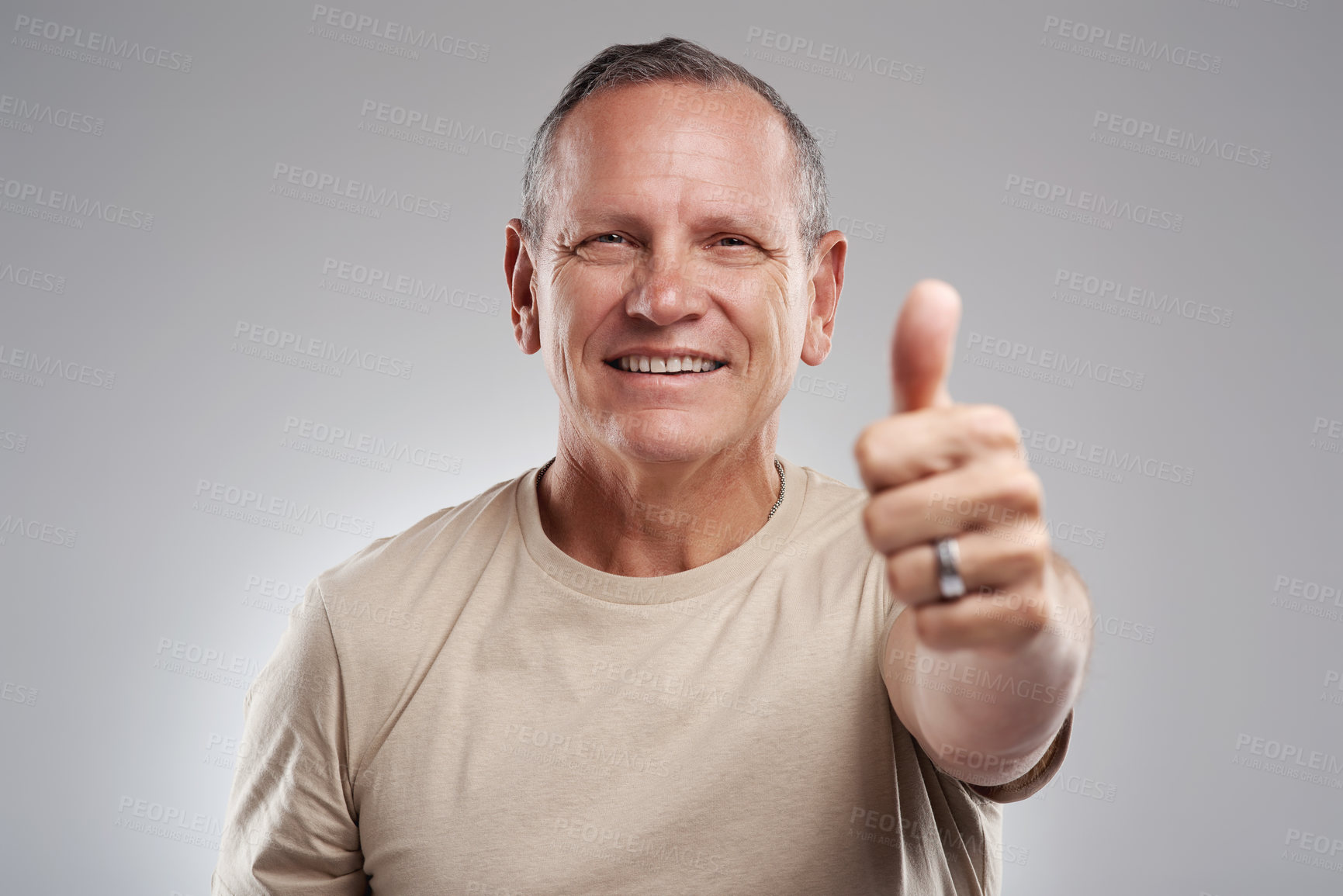 Buy stock photo Shot of a handsome mature man standing against a grey background in the studio and making a thumbs up gesture