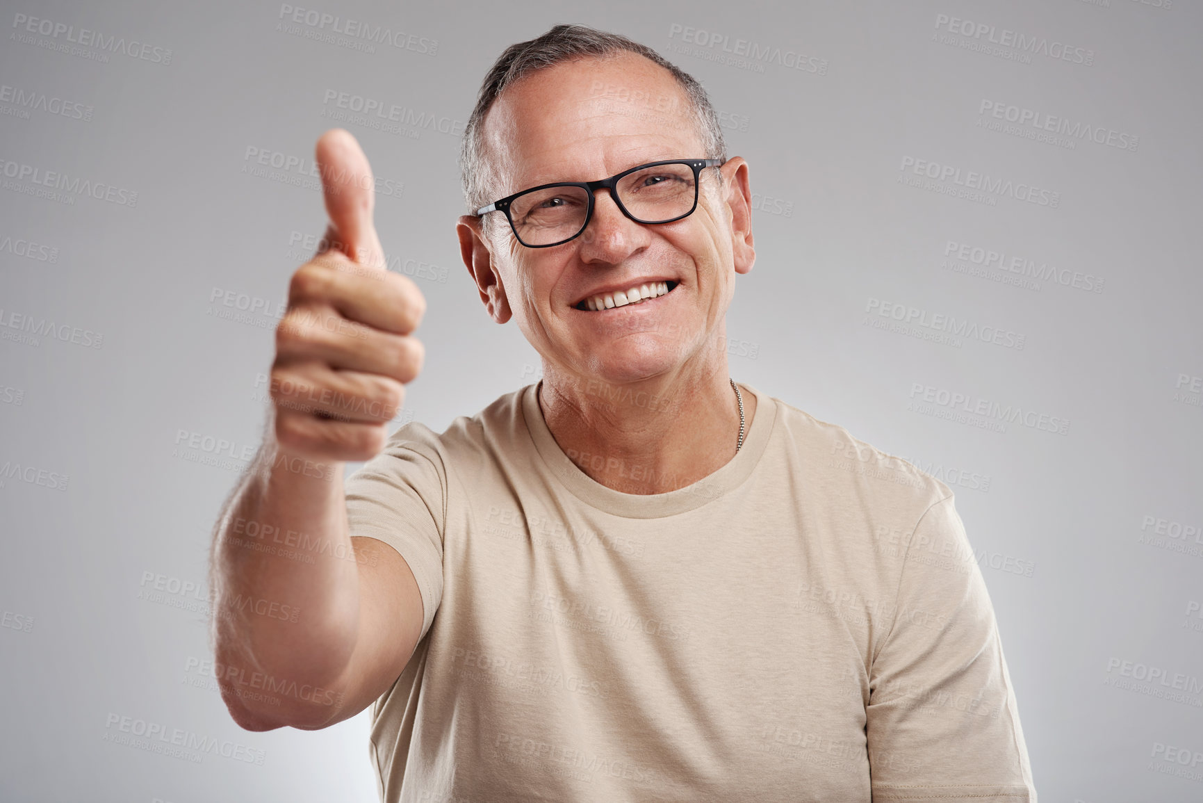 Buy stock photo Shot of a handsome mature man standing against a grey background in the studio and making a thumbs up gesture