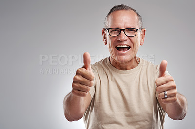 Buy stock photo Shot of a handsome mature man standing against a grey background in the studio and making a thumbs up gesture