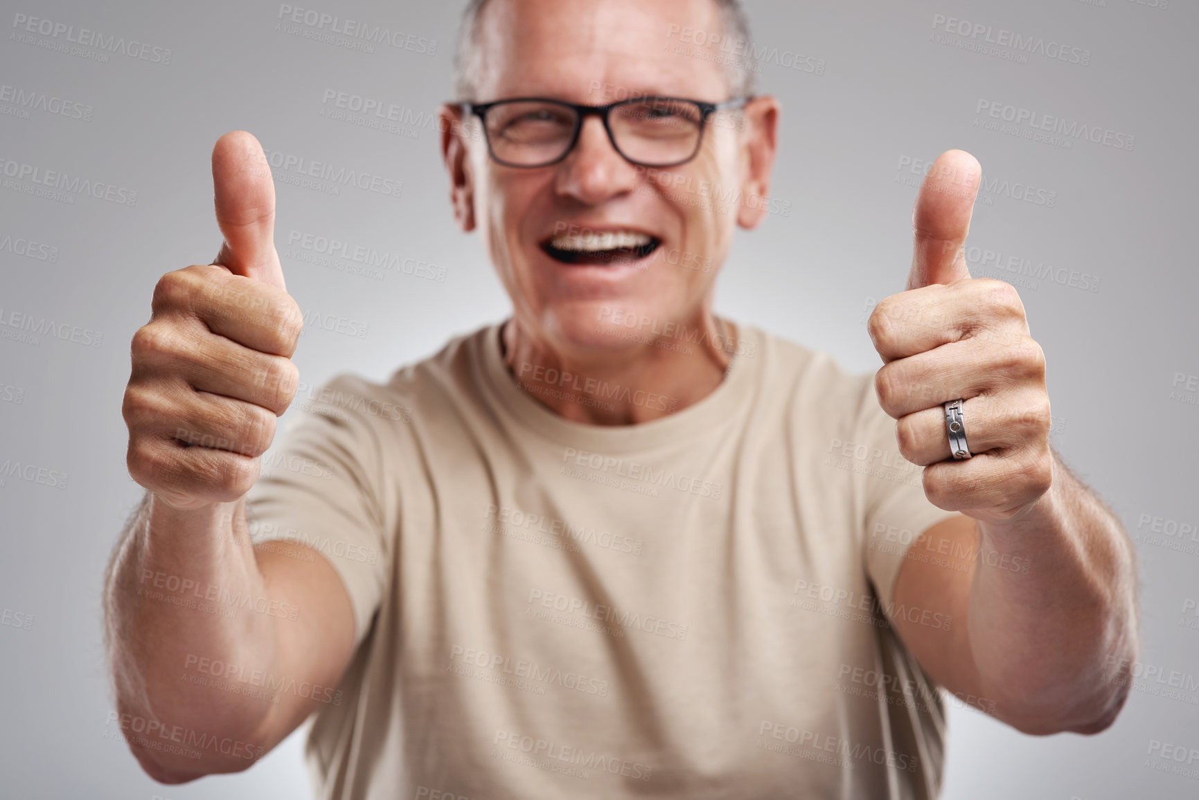 Buy stock photo Shot of a handsome mature man standing against a grey background in the studio and making a thumbs up gesture