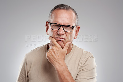 Buy stock photo Shot of a handsome mature man standing alone against a grey background in the studio and giving a disapproving look
