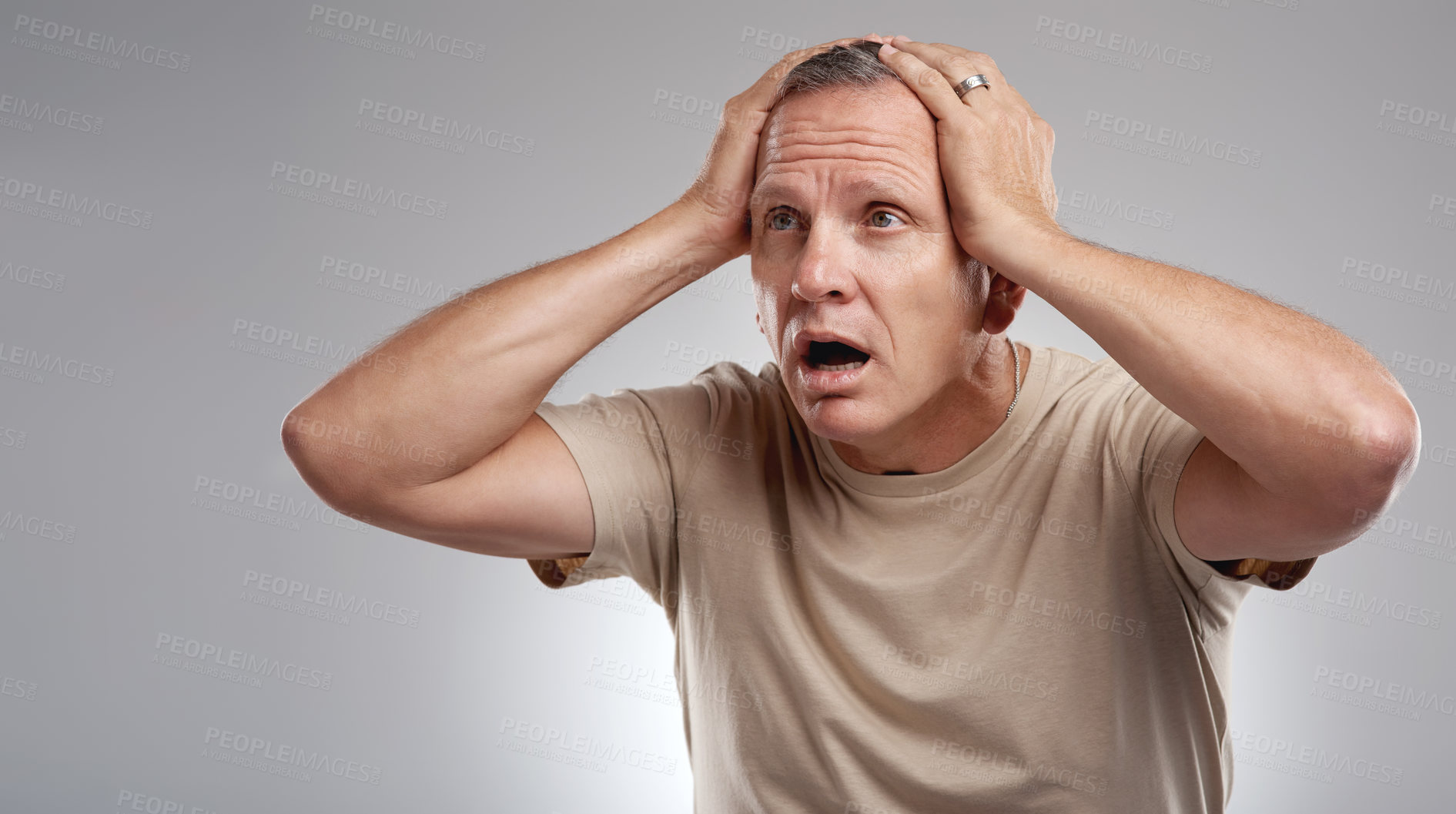 Buy stock photo Shot of a handsome mature man standing alone against a grey background in the studio and looking shocked