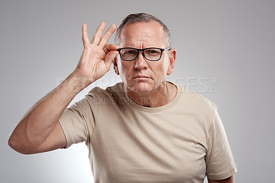 Buy stock photo Shot of a handsome mature man standing alone against a grey background in the studio and adjusting his glasses
