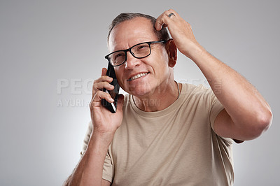 Buy stock photo Shot of a handsome mature man standing against a grey studio background and looking contemplative while using his cellphone