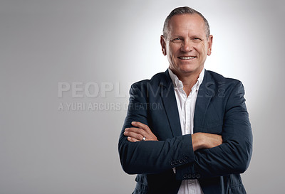 Buy stock photo Shot of a handsome mature businessman standing alone against a grey background in the studio with his arms folded