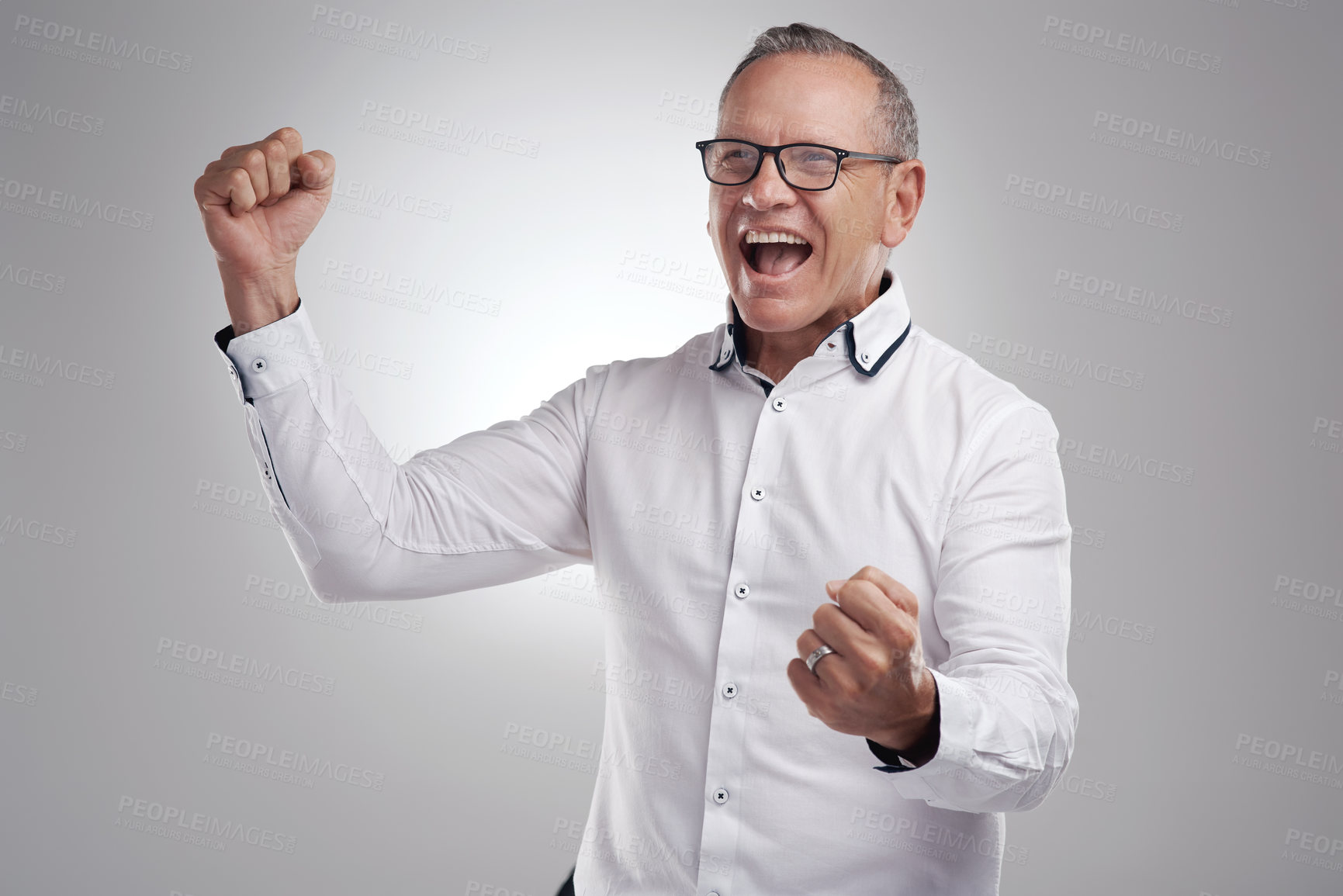 Buy stock photo Shot of a handsome mature businessman standing alone against a grey background in the studio and celebrating an achievement