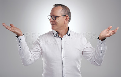 Buy stock photo Shot of a handsome mature businessman standing alone against a grey background in the studio and choosing between two options