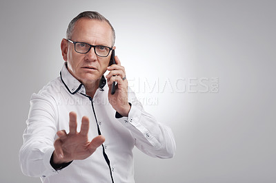 Buy stock photo Shot of a handsome mature businessman standing alone against a grey background in the studio and using his cellphone