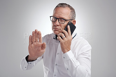 Buy stock photo Shot of a handsome mature businessman standing alone against a grey background in the studio and using his cellphone