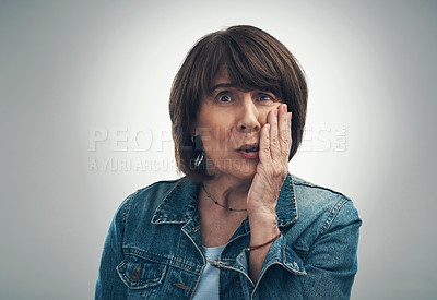 Buy stock photo Studio portrait of a senior woman looking scared against a grey background